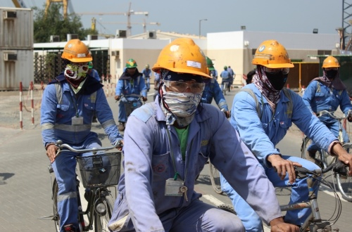 Workers cylcing at the BorWin3 site, wearing blue overalls and yellow safety helmets