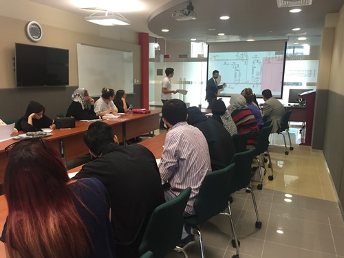 Students sitting at long desks, taking part in simulation exercise