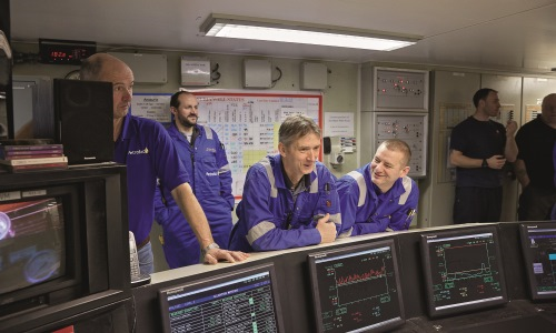 Men in blue overalls standing in control room